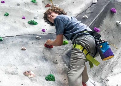 Teenager climbing on indoor rock wall.