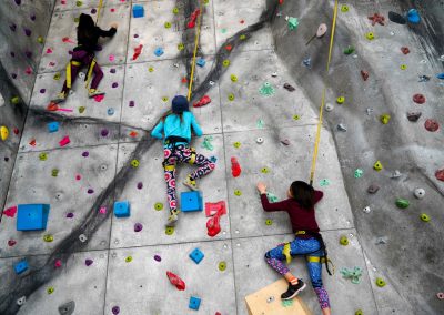 3 kids climbing on the rock climbing wall