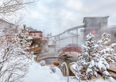 snow covered hot springs with steam coming off the water
