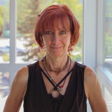 female massage therapist with red hair wearing lots of jewelry and a black tank top