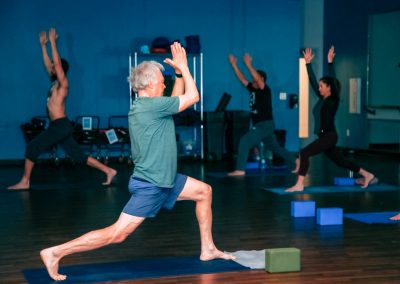 A male instructor guides a class in yoga poses