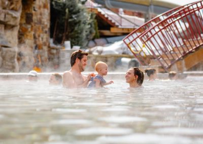 mother and father with young child soaking in the natural hot springs