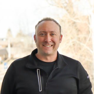 Female massage therapist wearing a necklace and green tank top