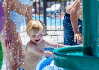 a young child plays in the green water table in the splash pool at old town hot springs